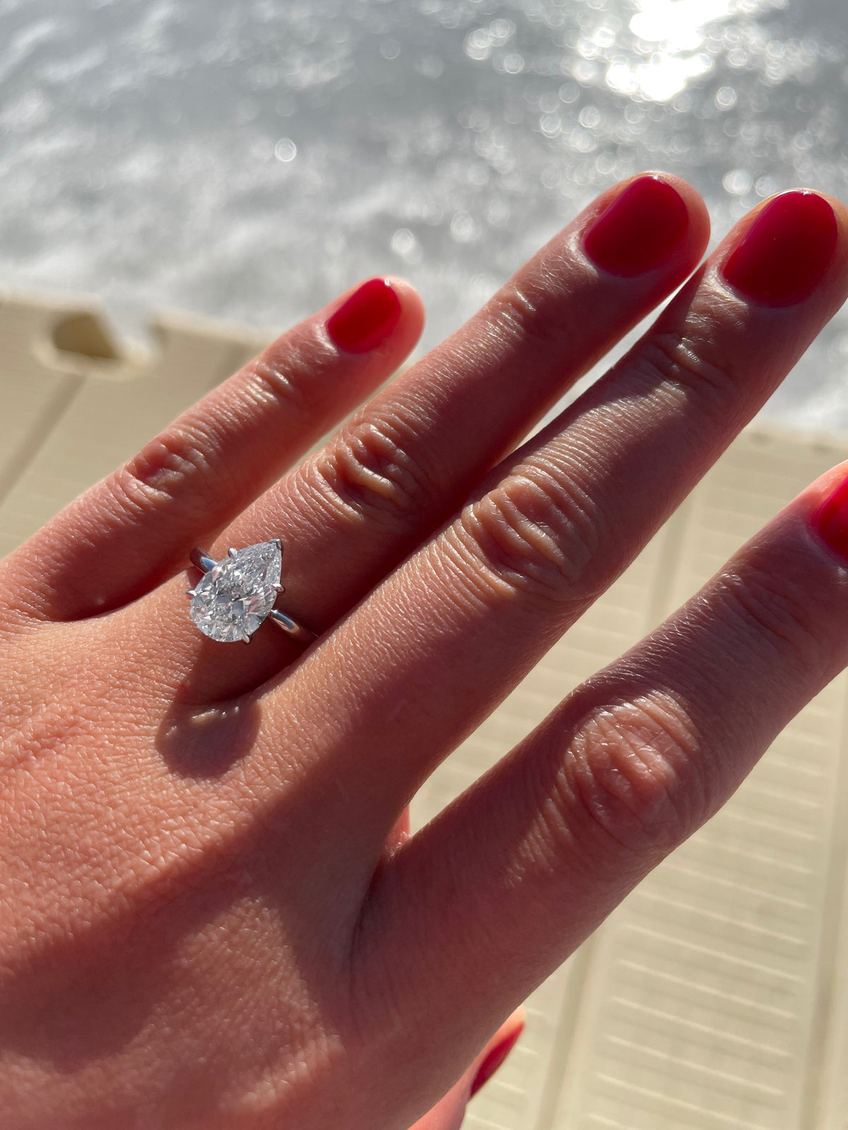 Pear cut diamond engagement ring on a hand with a neutral background