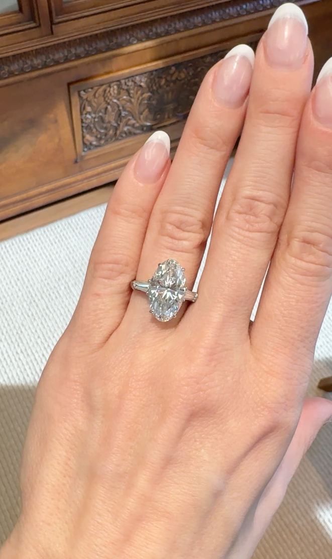 Moval diamond engagement ring on a hand with a neutral background