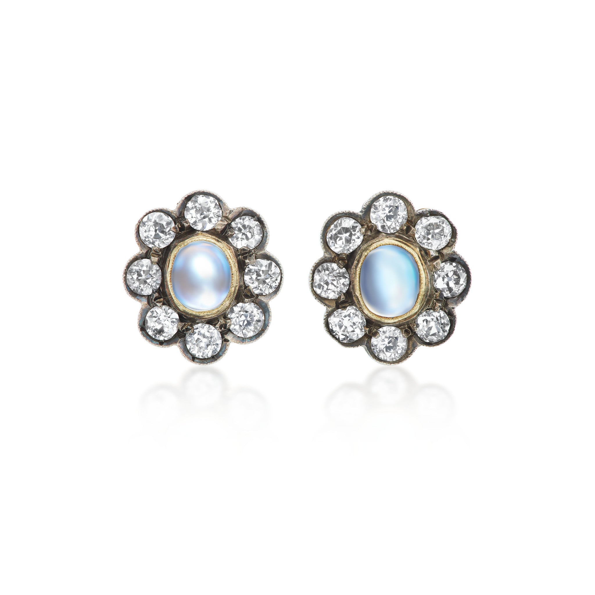 Antique earrings featuring lively bezel-set moonstones, with old mine-cut diamonds in a halo surround, set in silver topped gold.