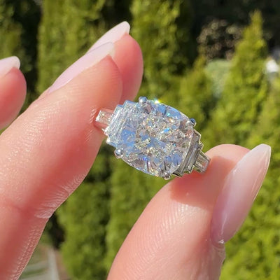 Art Deco cushion cut diamond engagement ring on a hand with a neutral background
