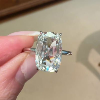 Cushion cut diamond engagement ring on a hand with a neutral background