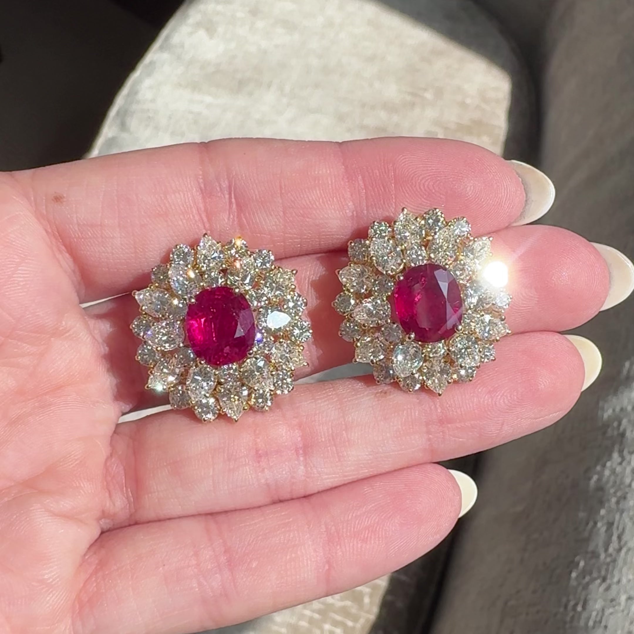 video of 18kt yellow gold ruby and diamond cluster earrings in hand sparkling in sunlight